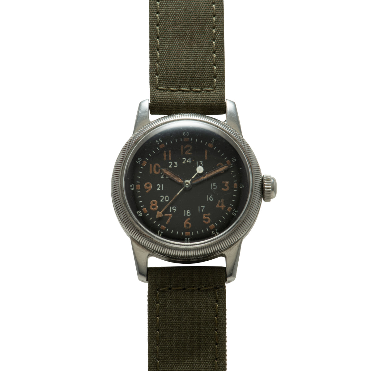 Waltham A-17 watch with black dial, 24-hour numerals in copper, silver case, and olive canvas strap.