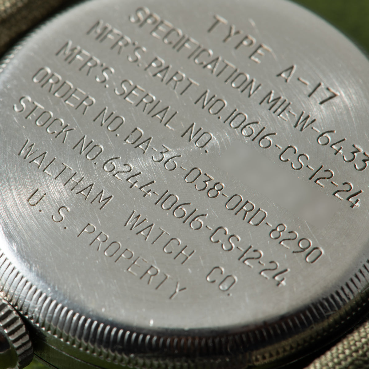 Silver watch case back engraved with "Type A-17" and military specification markings including Waltham manufacturer details a