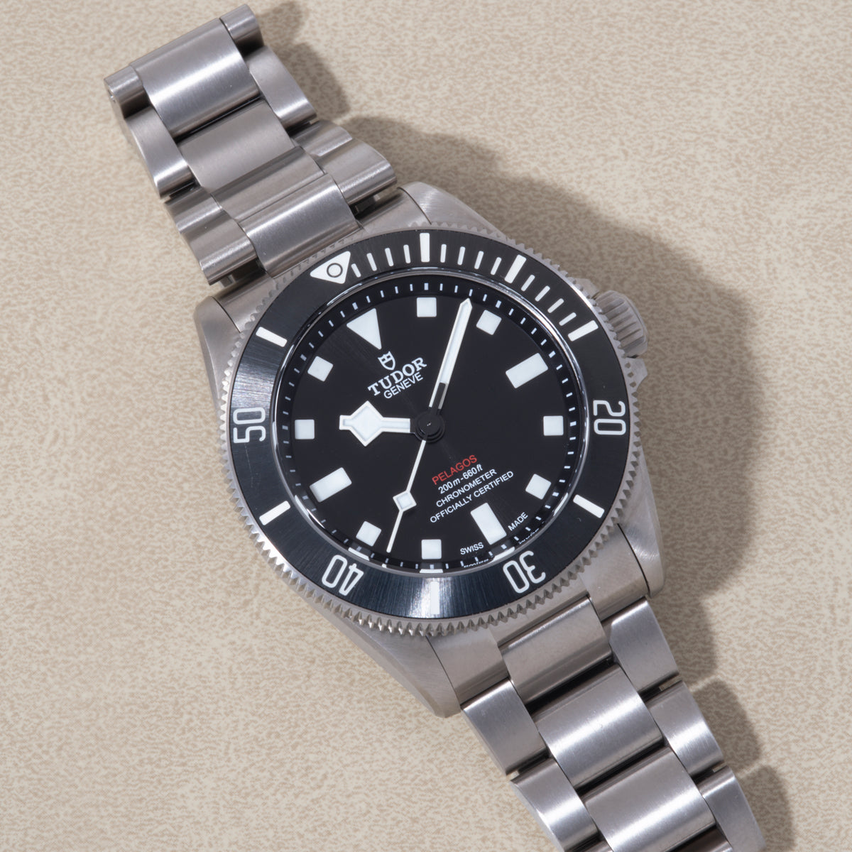 Tudor Pelagos 39 stainless steel dive watch with black dial, white hour markers, and matching metal bracelet.