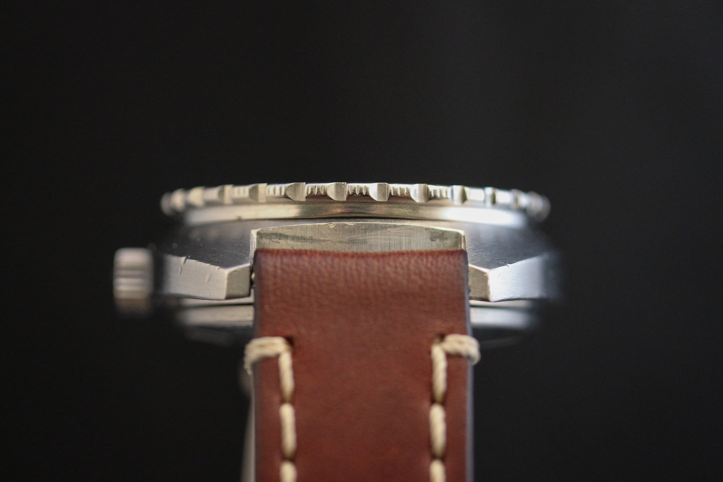 Close-up side view of the DOXA Sub 300T Sharkhunter Aqua Lung dive watch with a brown leather strap, silver serrated bezel and crown—an iconic DOXA diver’s timepiece set against a black background.
