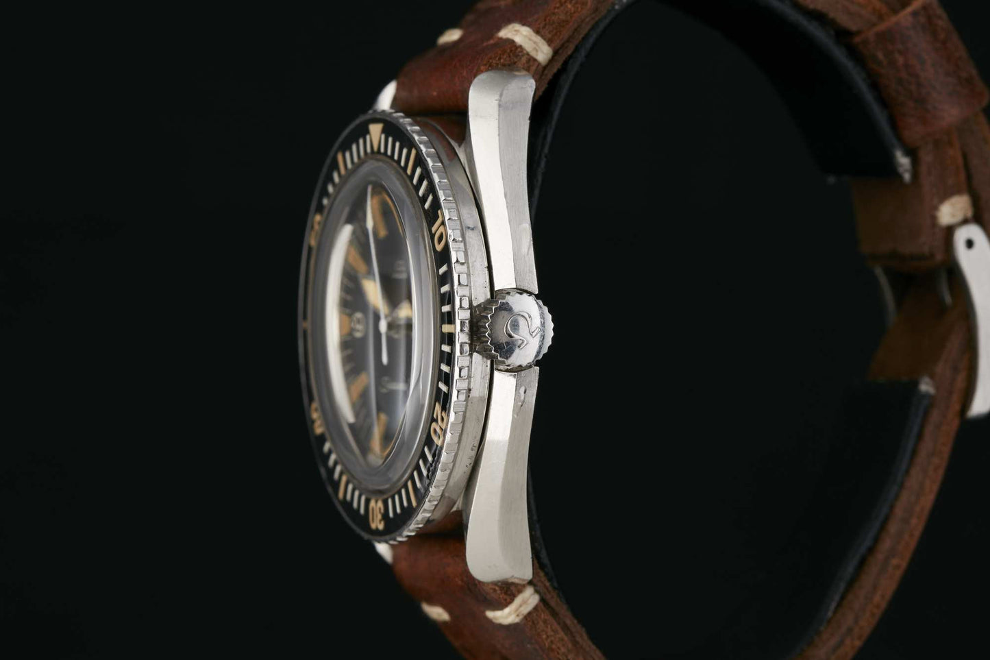 A close-up side view of the Omega Seamaster 300 by Omega, featuring a brown leather strap, silver case, detailed crown, and a bezel with minute markings. The black background highlights its expert craftsmanship. Detailed description coming soon!.
