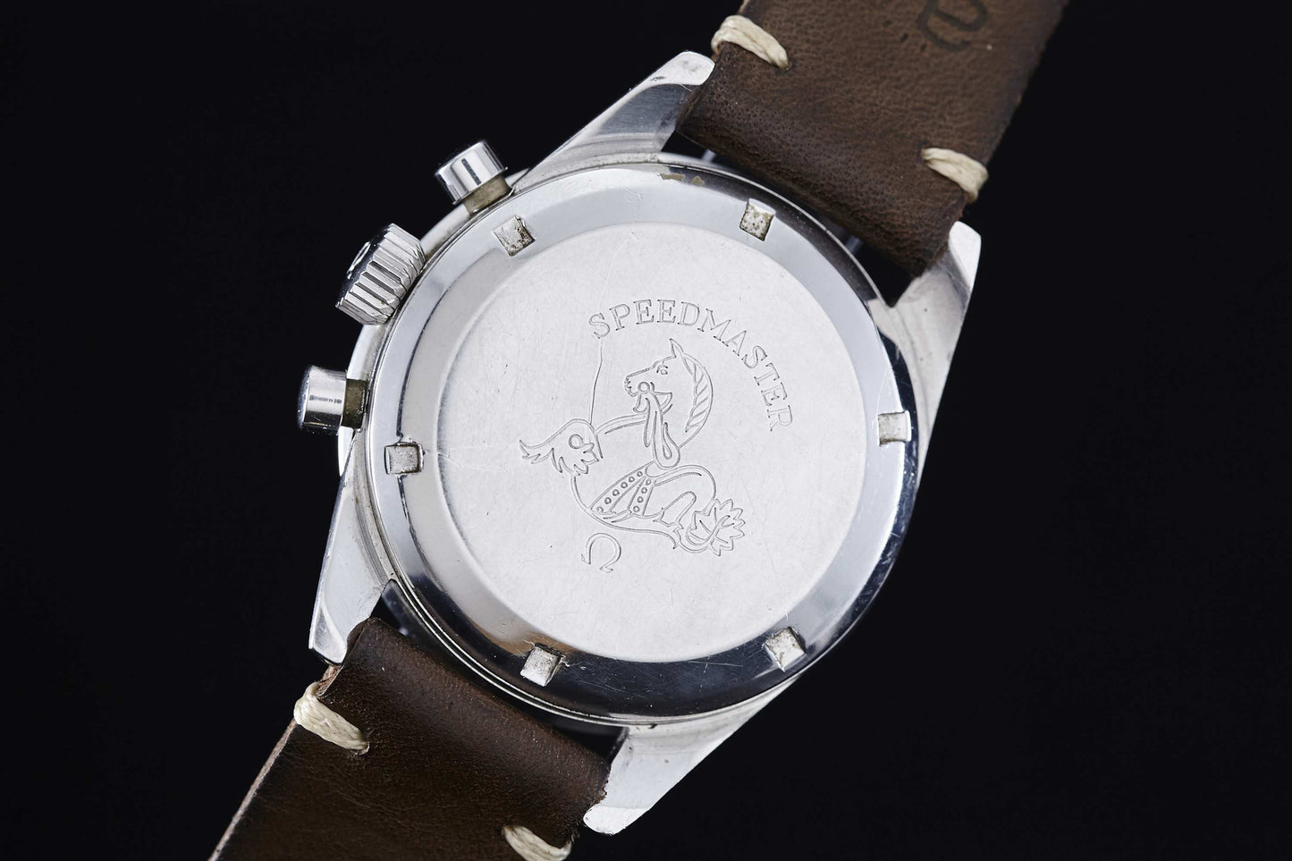 The back of the Omega Speedmaster Ed White by Omega features a brown leather strap and an engraved case back with "SPEEDMASTER" and a seahorse (hippocampus) motif.