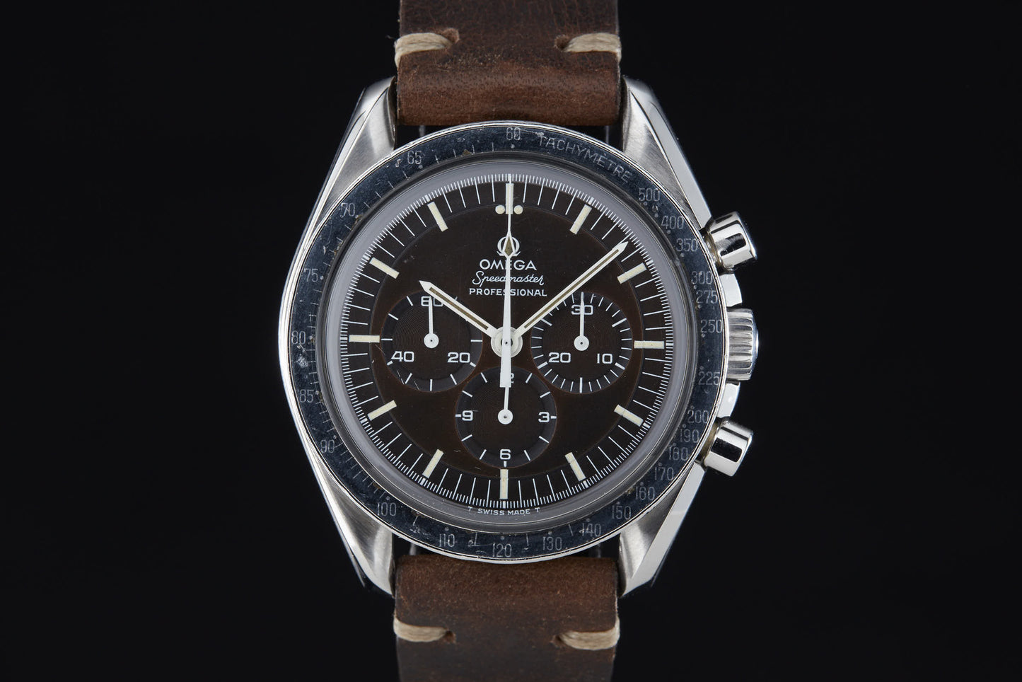A detailed look at the Omega Speedmaster Professional by Omega, featuring a black dial with white indices, three subdials, and a brown leather strap—famed for its role in the Apollo Moon Landing—displayed against a black background.