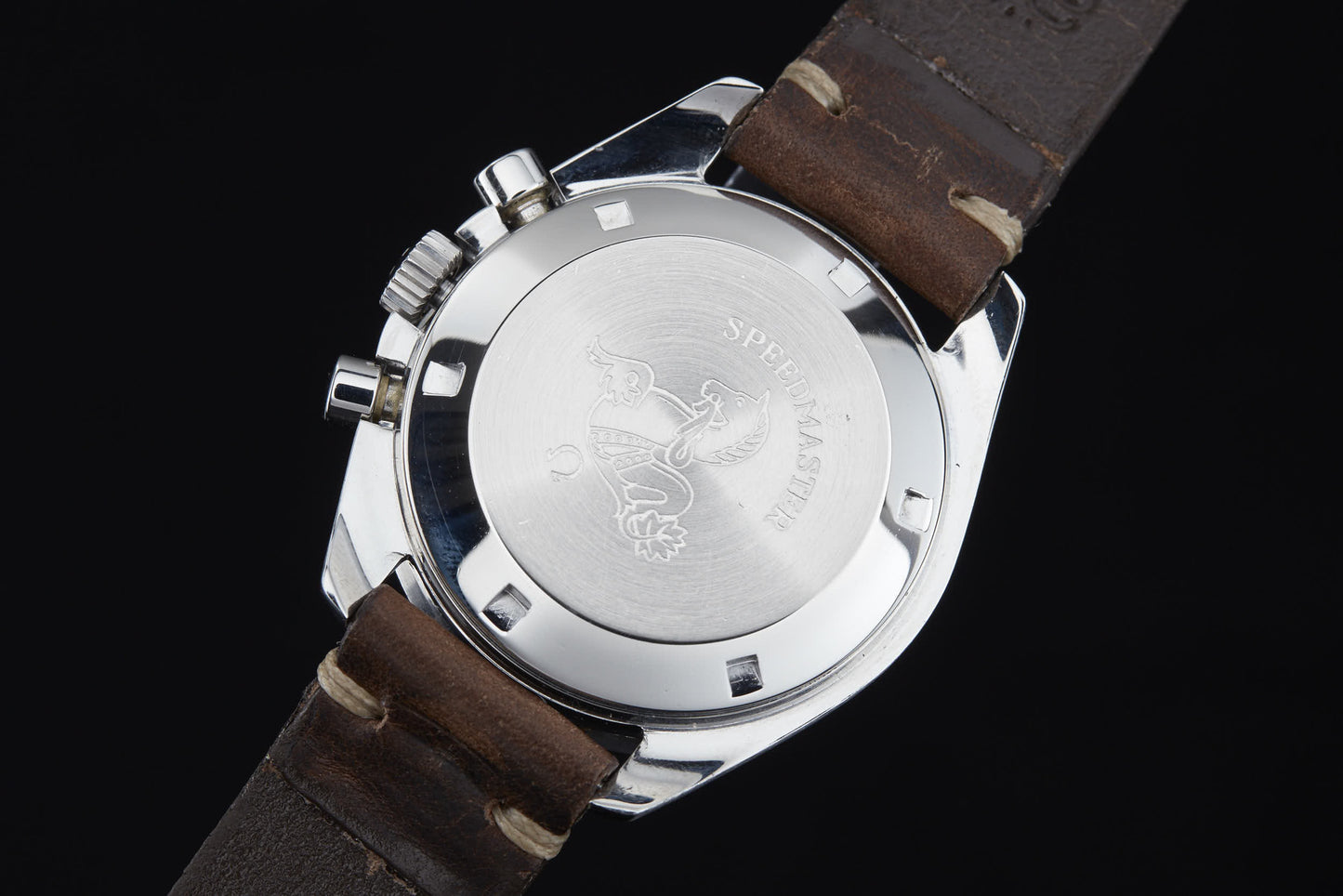 A close-up of the stainless steel case back of the Omega Speedmaster Professional by Omega, featuring an engraved seahorse and “Speedmaster” inscription, honoring its legacy in the Apollo missions and Moon Landing history. Brown leather strap included.