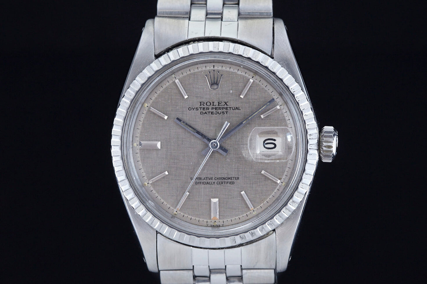 The Rolex Datejust 1601 Grey Linen features a gray textured dial, silver hour markers, a date window at 6, and comes on a stainless steel bracelet—a classic vintage wristwatch from Rolex.