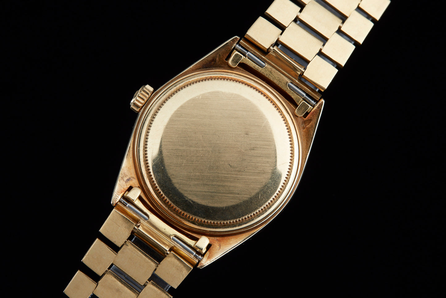 Solid gold vintage Rolex Datejust case back on black background