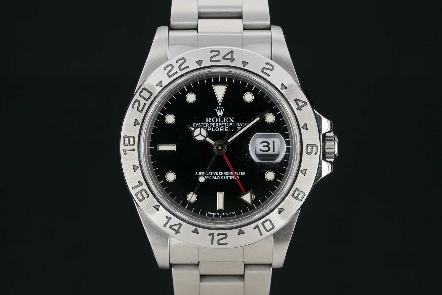 The Rolex Explorer II by Rolex features a stainless steel case, black dial with white hour markers, date at 3 o’clock, red GMT hand, and an engraved 24-hour bezel for easy dual time zone tracking.