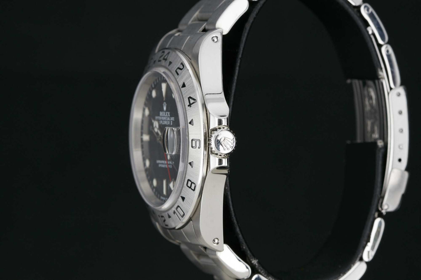 Close-up side view of the Rolex Explorer II by Rolex, a luxury sport wristwatch featuring a stainless steel band and 24-hour bezel, shown against a black background to highlight the crown and case details.