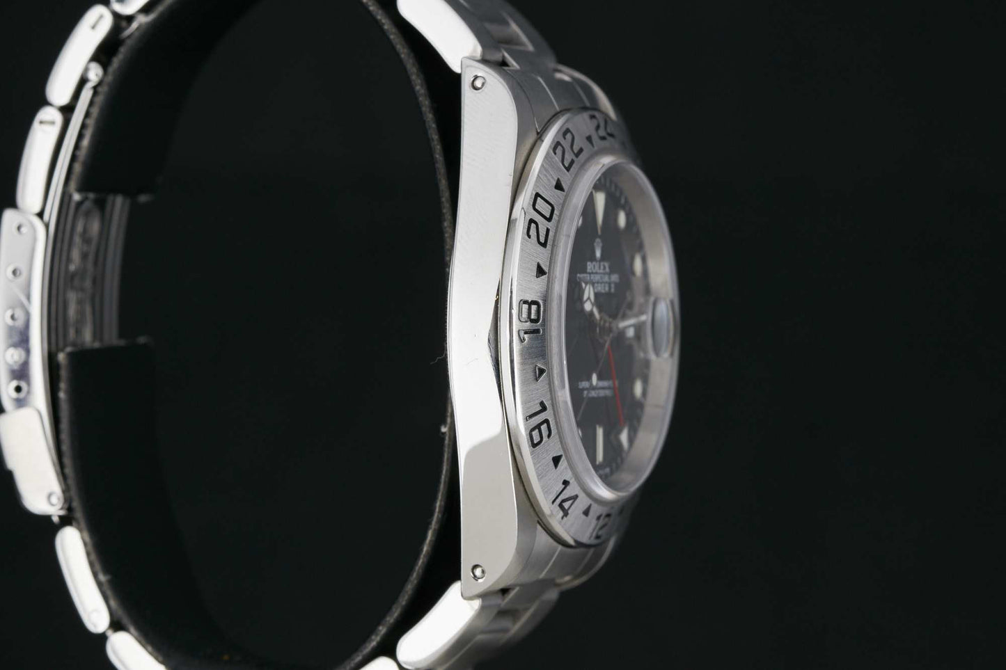 A side view close-up of the Rolex Explorer II by Rolex, featuring a silver case, black dial, and 24-hour bezel, set against a black background.