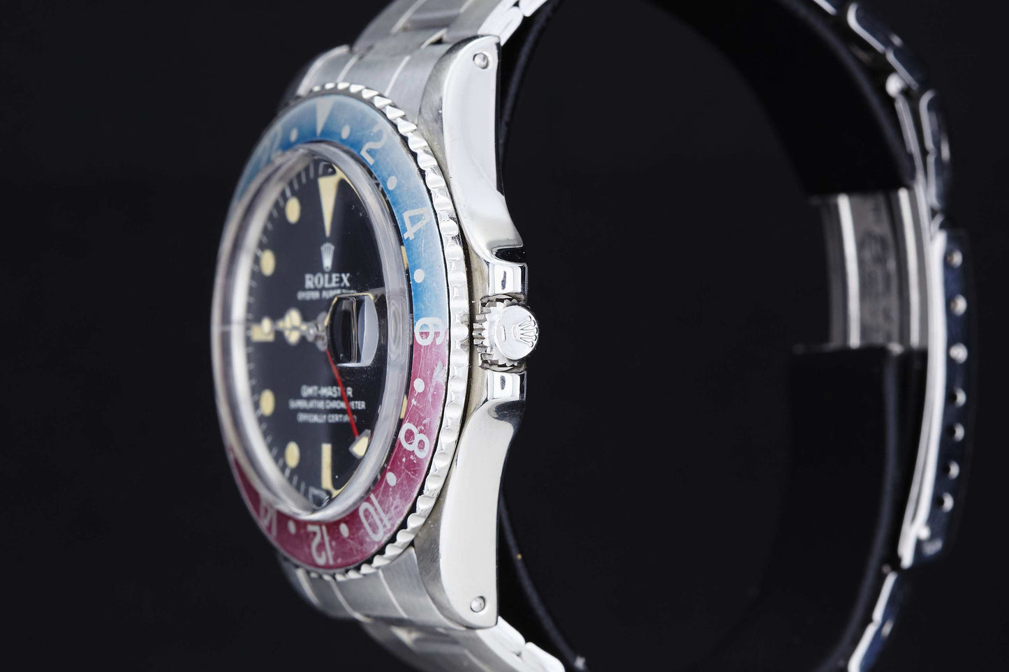 A close-up side view of the Rolex GMT Master 1675, featuring a silver metal band and iconic red and blue bezel, highlights its detailed craftsmanship and Rolex crown logo—an enduring classic for vintage watch enthusiasts.