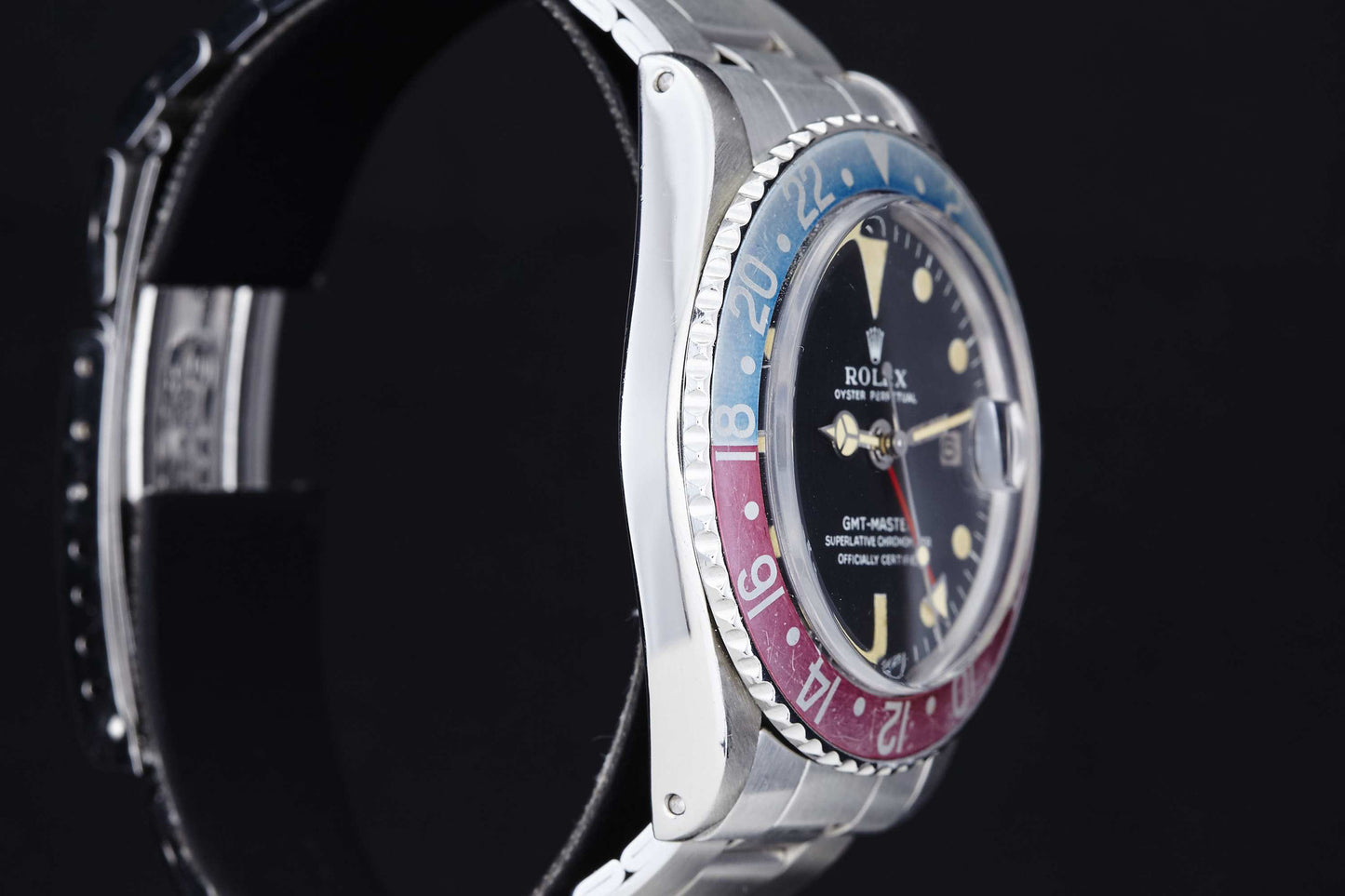 A close-up side view of the Rolex GMT Master 1675 by Rolex, featuring a red and blue bezel, black dial, and silver metal band, set against a black background. This vintage watch displays the time as 10:09 and is ideal for daily wear.