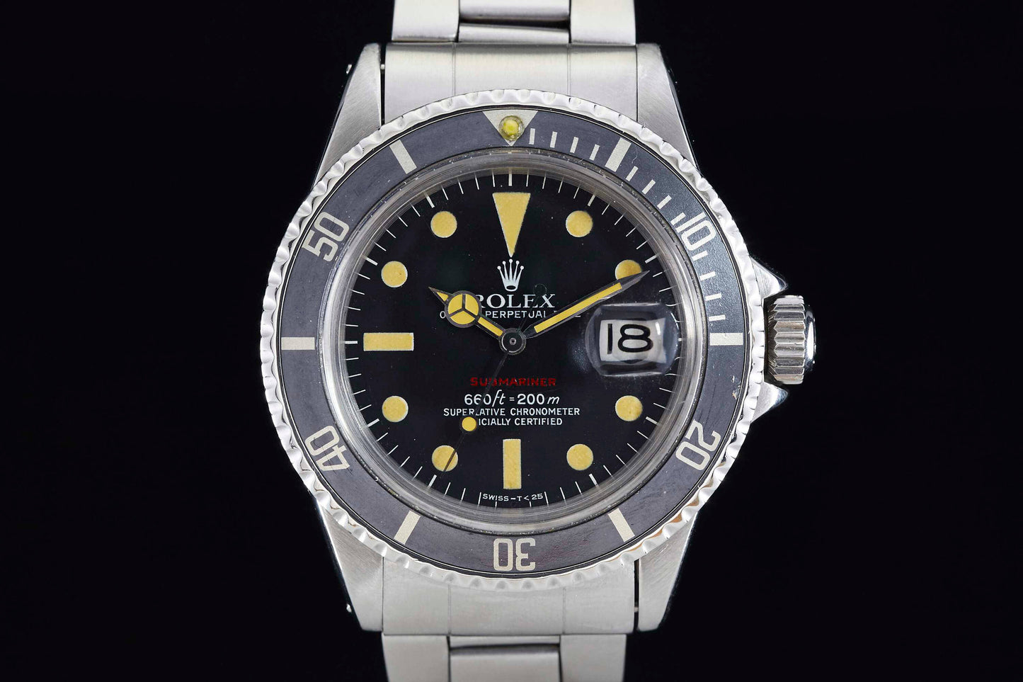 A close-up of the Rolex Submariner shows its stainless steel band, black bezel and dial, large yellow markers, date window at 3 o’clock, and the signature Rolex crown logo at 12.