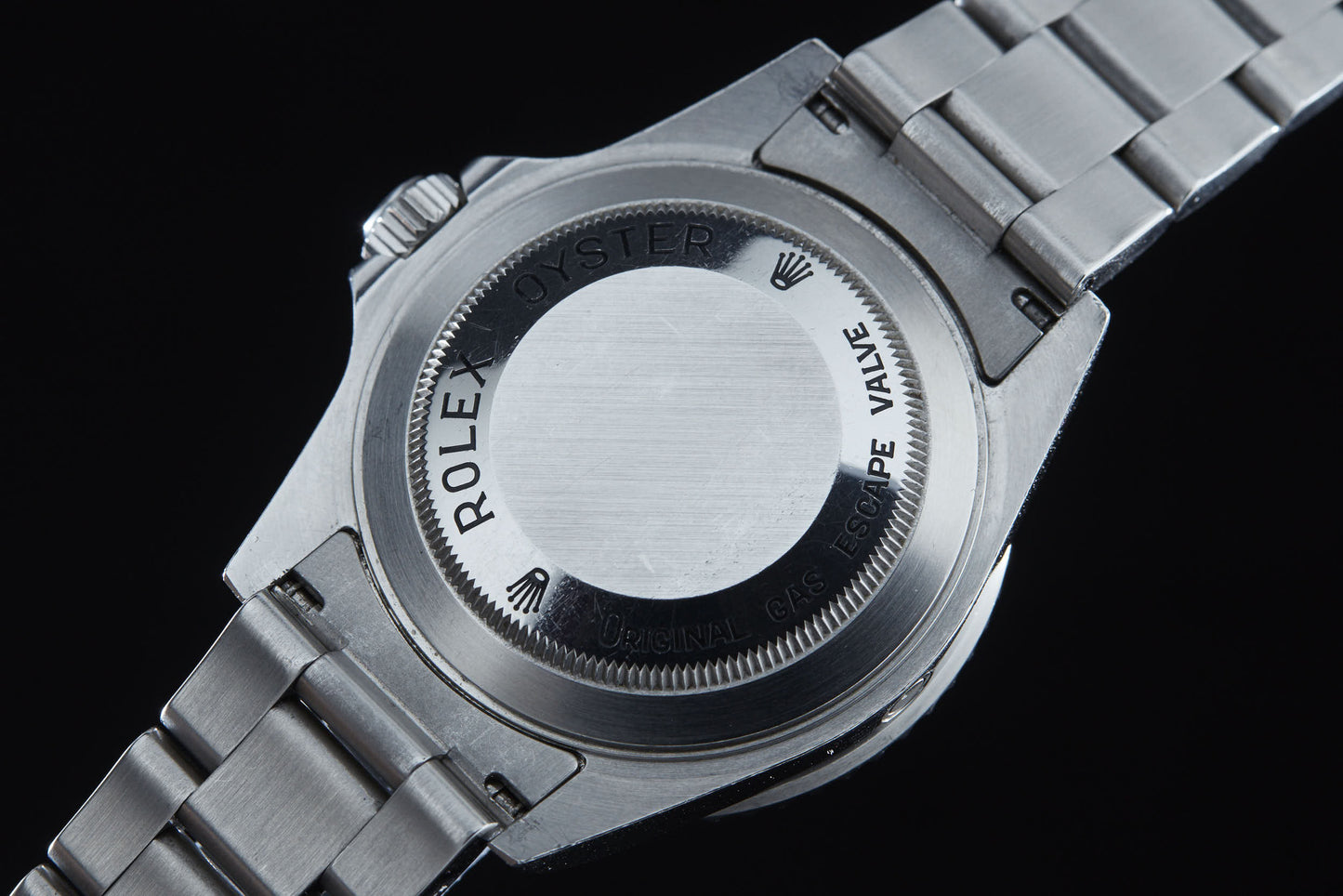 Close-up of the back of a Rolex Sea Dweller by Rolex, featuring an engraved ROLEX OYSTER and ORIGINAL GAS ESCAPE VALVE—trusted by COMEX divers for extreme saturation diving—with its signature metal bracelet.