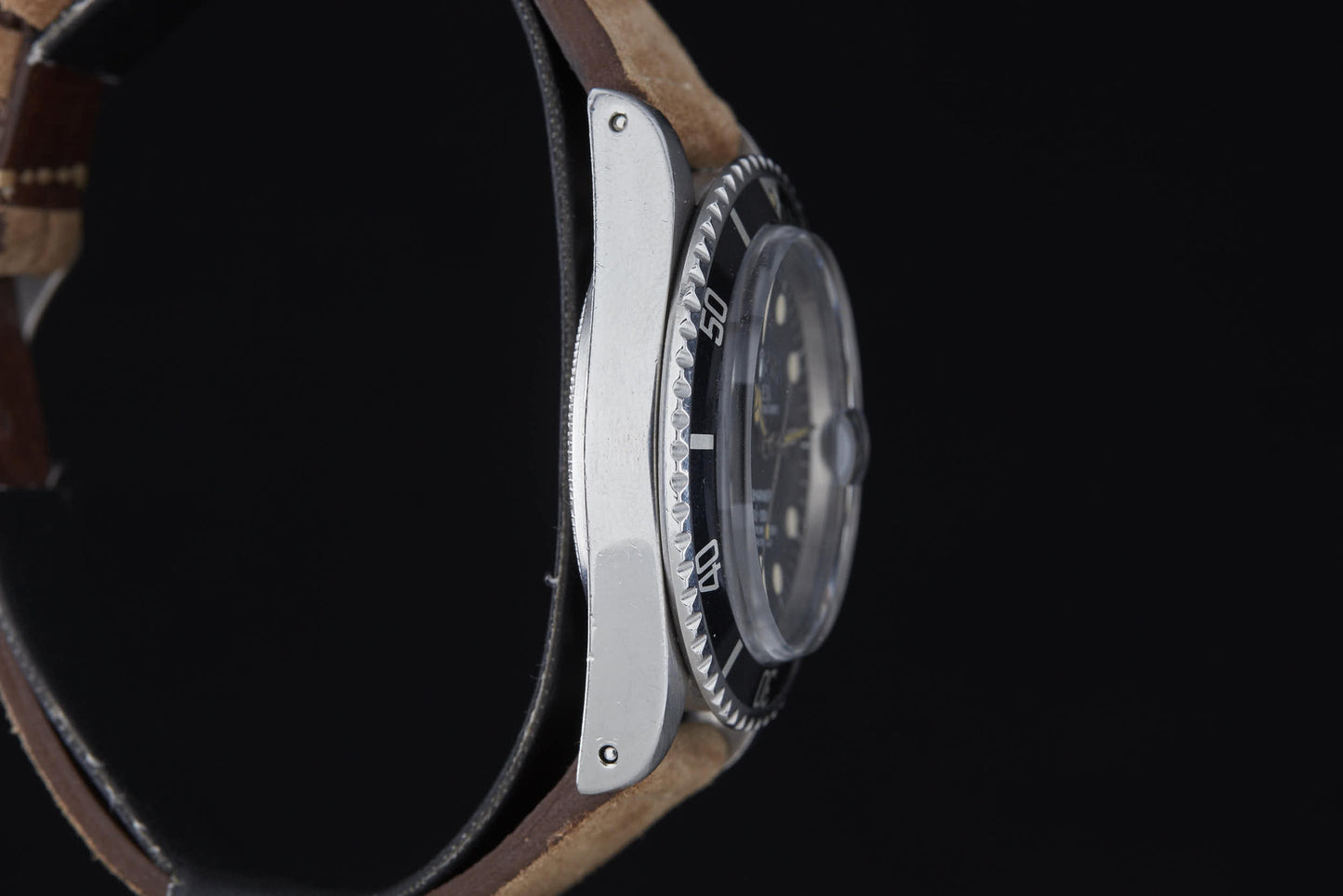 Side view of a Rolex Submariner by Rolex, Reference 1680, featuring a brown leather strap, black and silver bezel, and slightly domed glass over the dial, set against a black background.