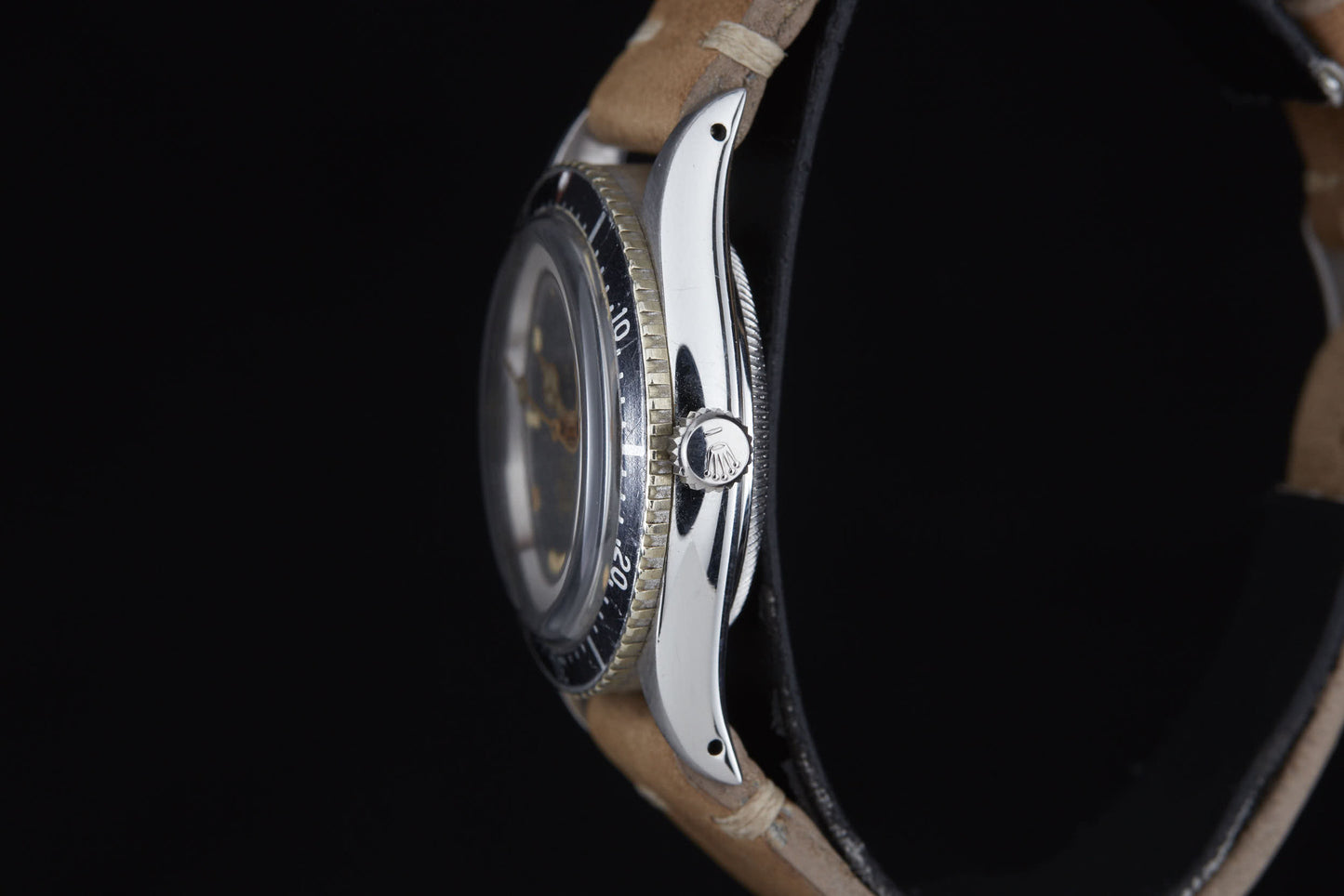 Side view of the Rolex Turn-O-Graph by Rolex, featuring a silver case, black rotating bezel, and tan leather strap against a black background. Visible crown and bezel markings echo classic Rolex sports style.