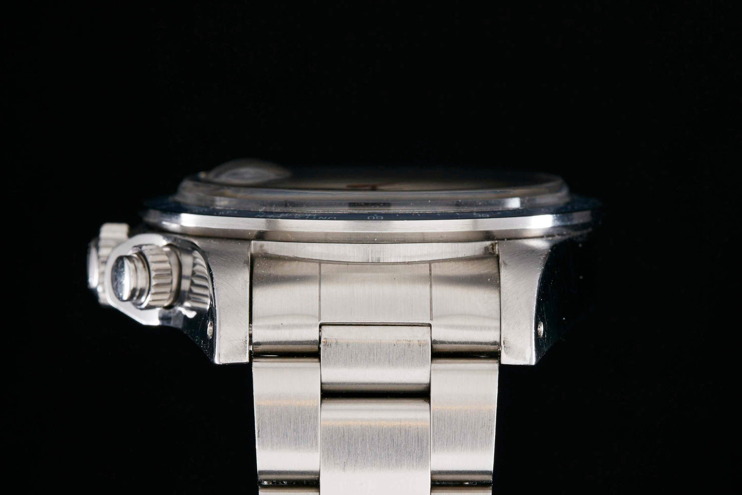 Close-up side view of the Tudor Monte Carlo 9420/0 wristwatch by Tudor, featuring a silver case and metal band with prominent crown, set against a black background—a nod to classic vintage Tudor designs.