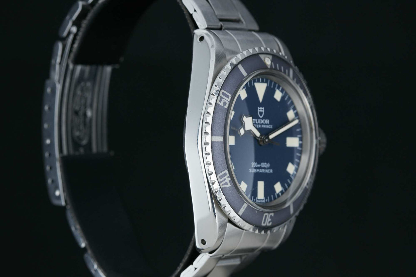 A close-up of the Tudor Submariner Snowflake by Tudor, featuring a stainless steel case, blue dial and bezel, luminous markers, and metal bracelet set against a black background. Detailed description coming soon!.