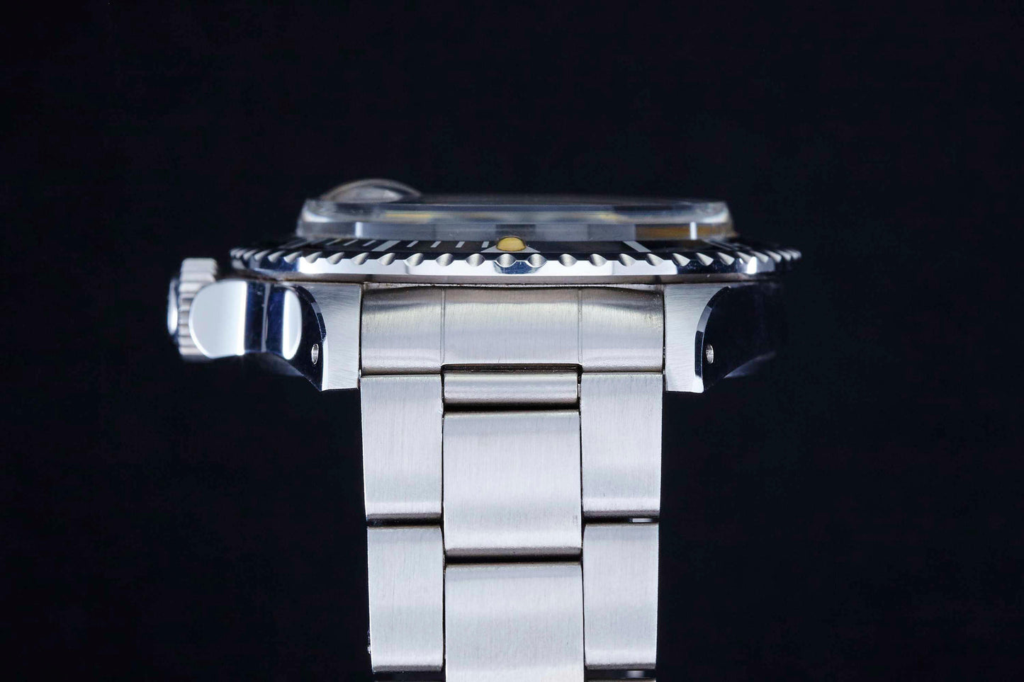Close-up side view of the Tudor Snowflake Submariner by Tudor, featuring a stainless steel case, metal link band, and ridged bezel, set against a black background.