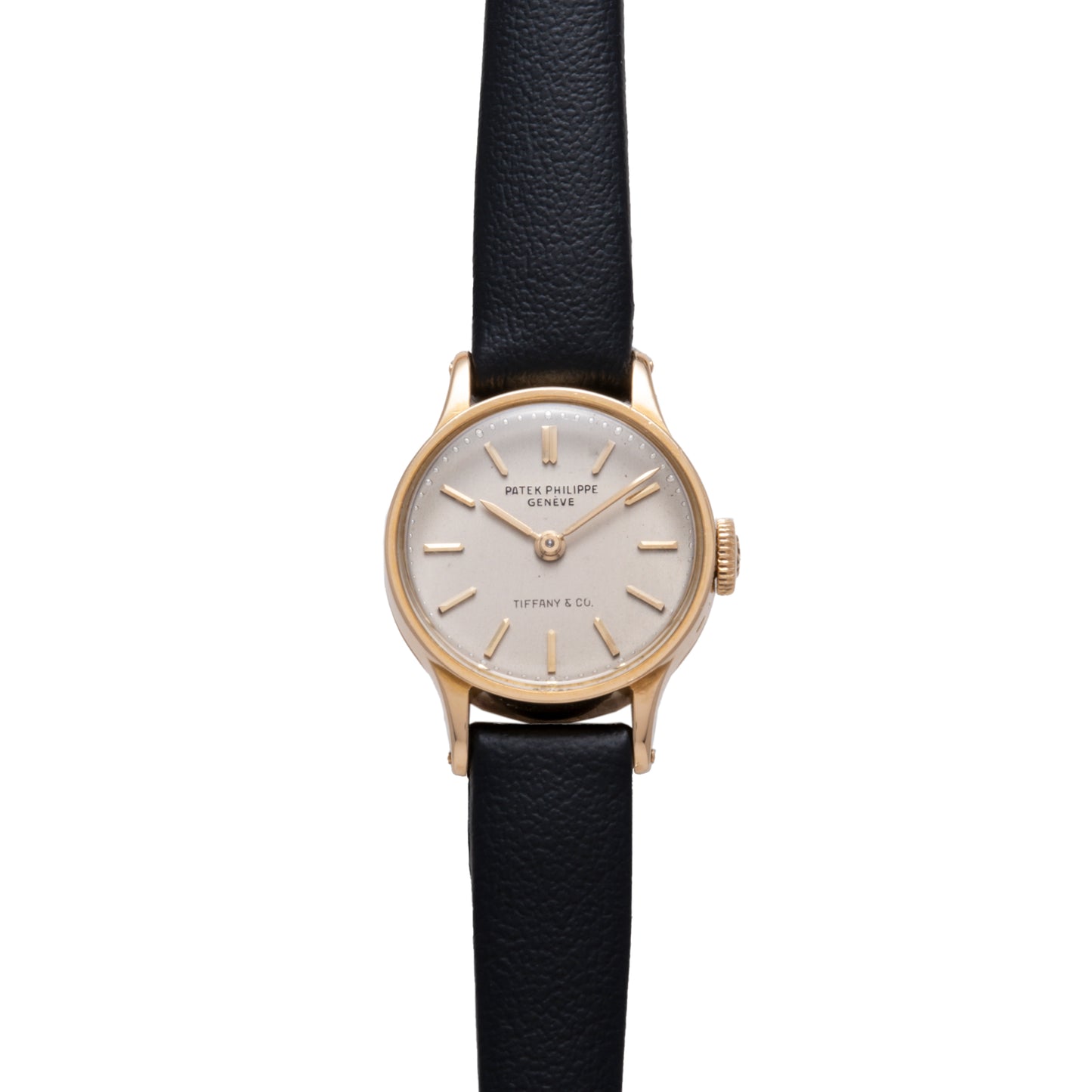 The Patek Philippe Calatrava 'Tiffany & Co' is a ladies dress watch featuring a round 18K yellow gold case, silver dial with gold markers and hands, black leather strap, and Tiffany & Co co-branding on the dial.