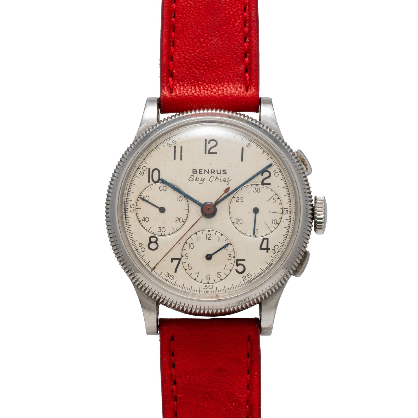 The Benrus Sky Chief is a vintage pilot chronograph with a white dial, three subdials, black numerals, red leather strap, silver case, and two side buttons.