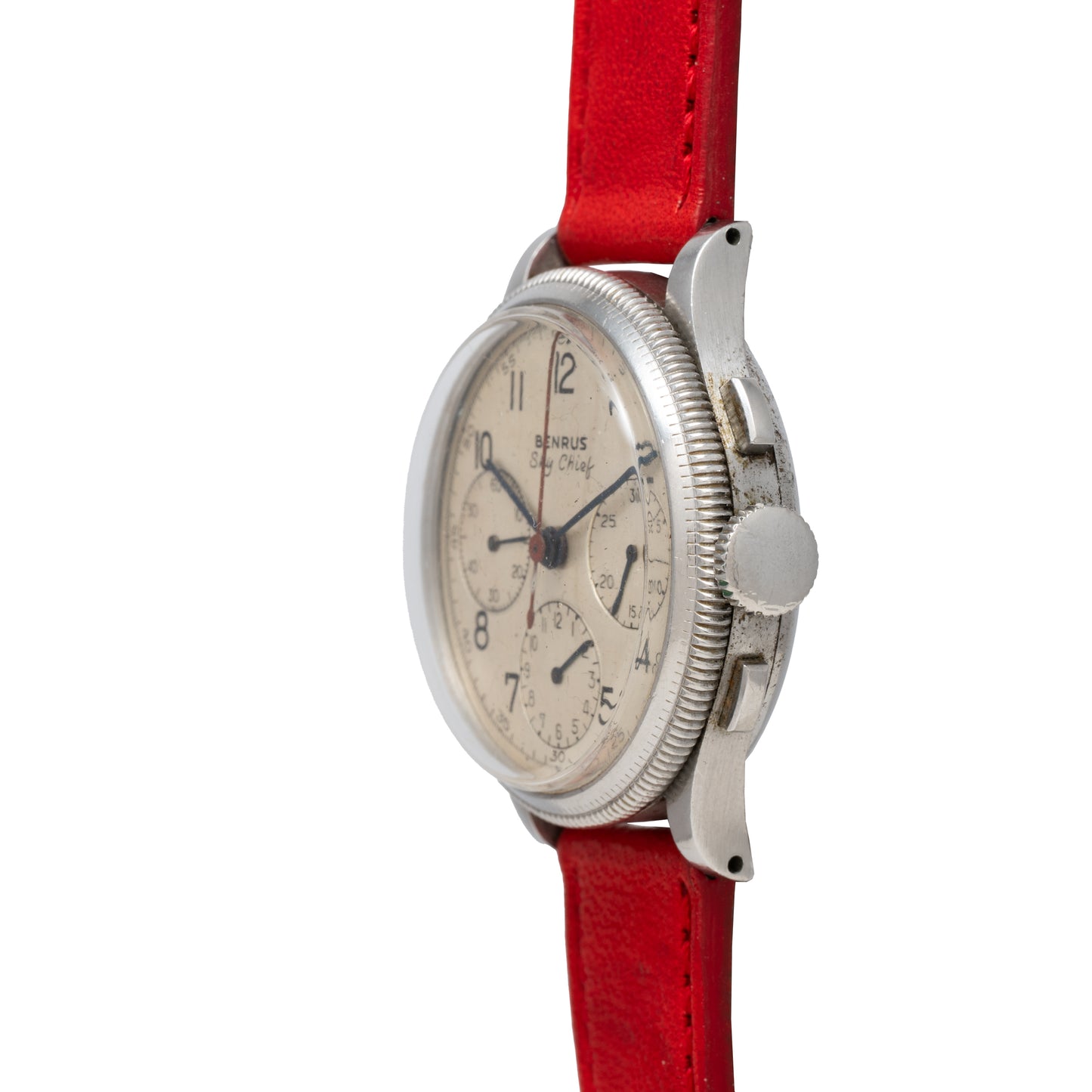 The Benrus Sky Chief pilot chronograph by Benrus is shown from a side angle, featuring a white dial with multiple subdials, a stainless steel case, and a bright red leather strap.