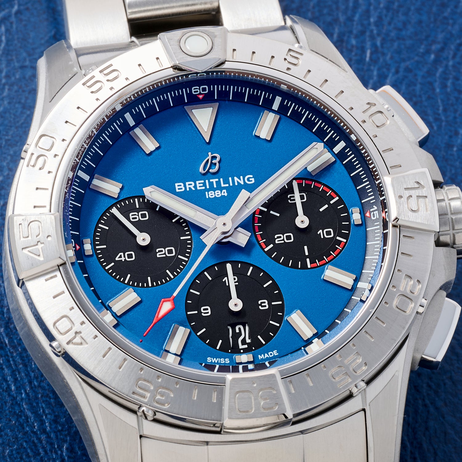 Close-up of the Breitling Avenger B01 Chronograph 42 aviation watch by Breitling, featuring a blue dial, three black subdials, silver hour markers, stainless steel bezel, blue fabric strap, COSC-certified automatic movement, and date at 6 o’clock.