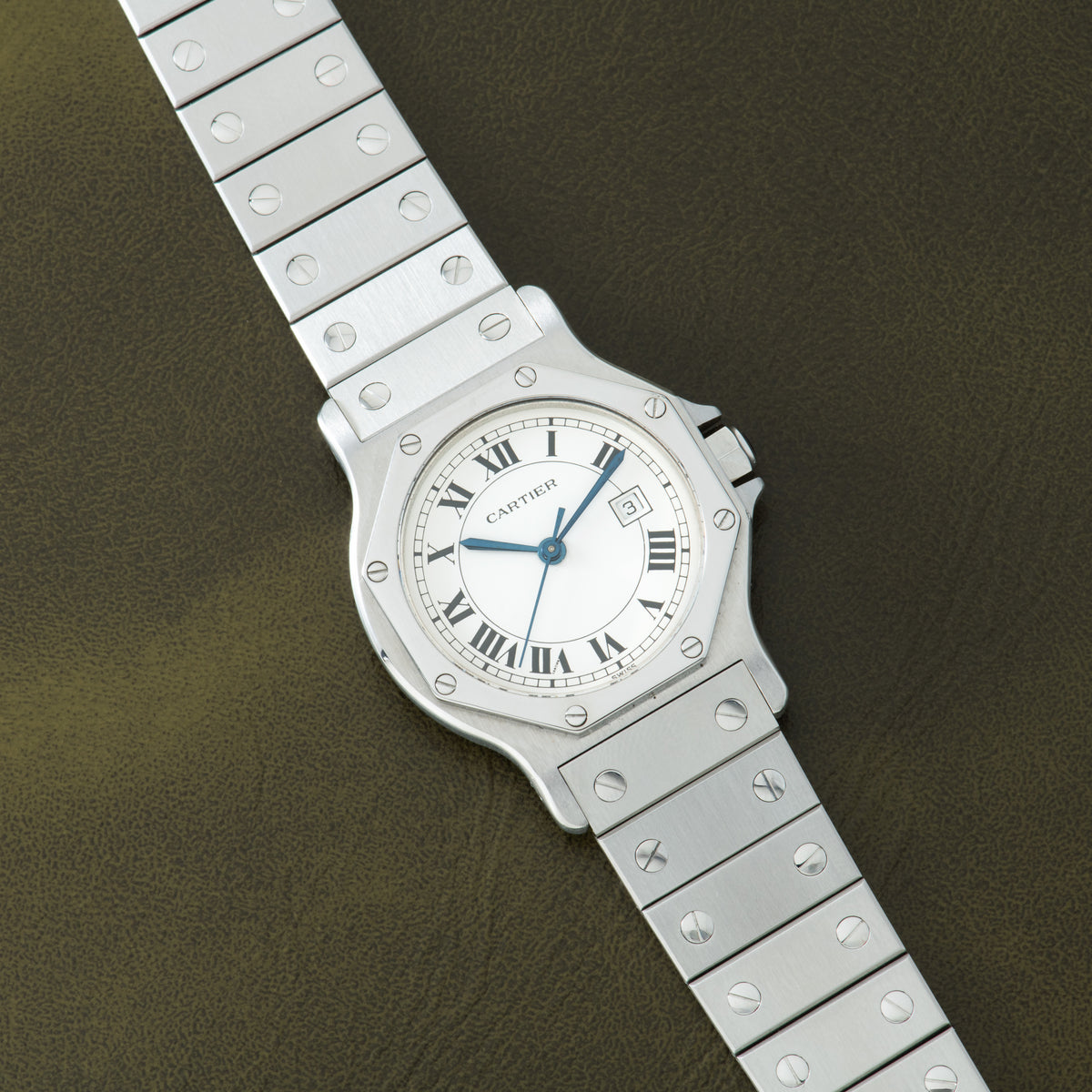 Stainless steel Cartier Santos watch with octagonal case, white dial, Roman numerals, blue hands, and matching bracelet with 