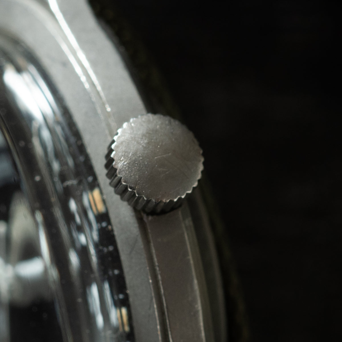 Stainless steel watch crown with serrated knurled edge and textured surface.