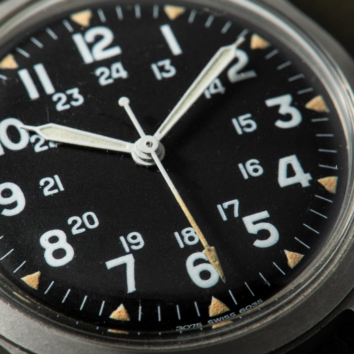 Hamilton watch with black dial, white Arabic numerals, luminous hands, and triangular hour markers in gold and white.