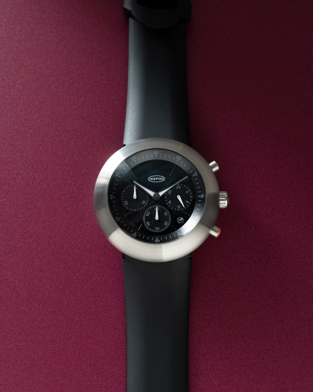Black chronograph watch with silver round case, black dial with subdials, and black rubber strap.