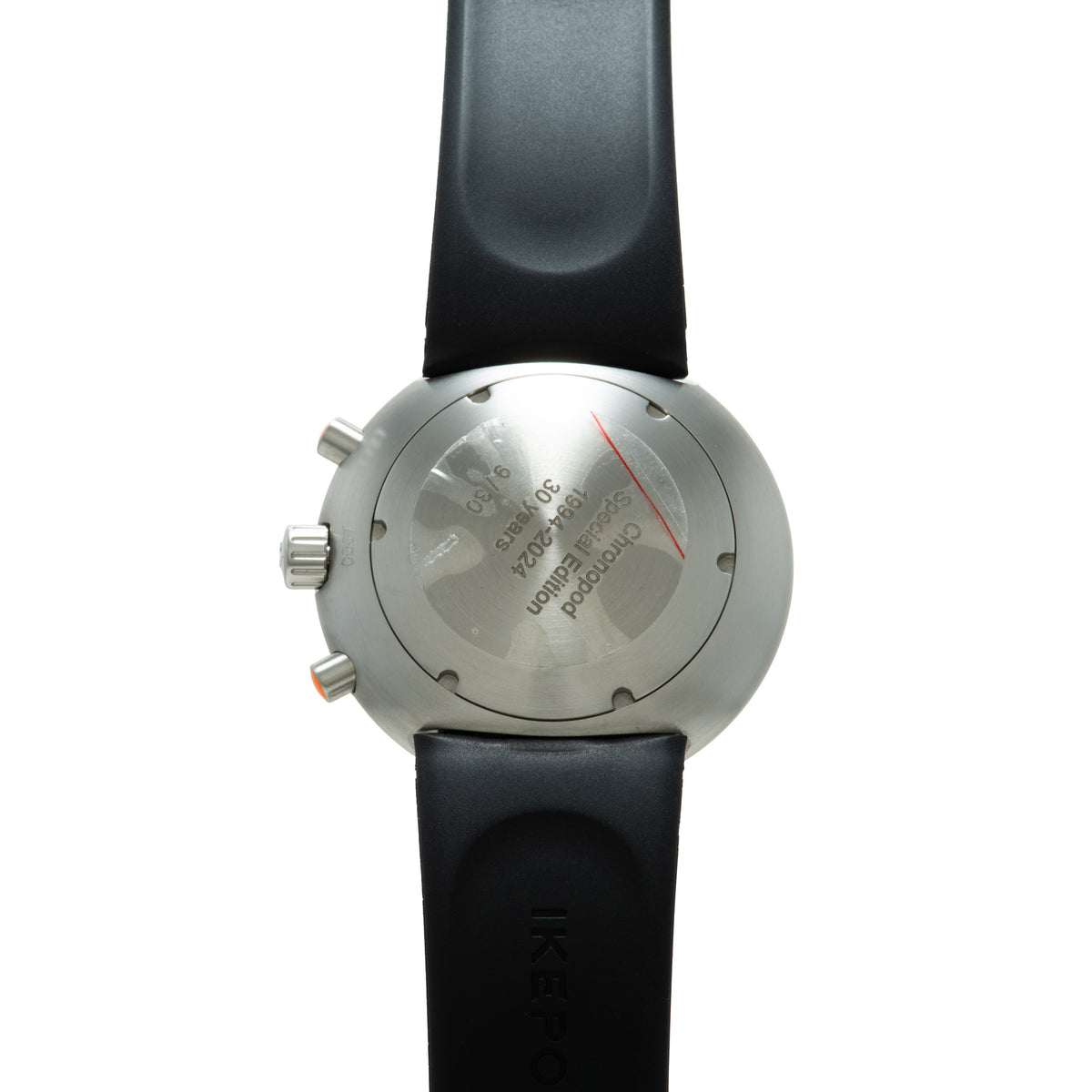 Stainless steel chronograph watch with black rubber strap, viewed from the case back showing engraved text and red chronograp