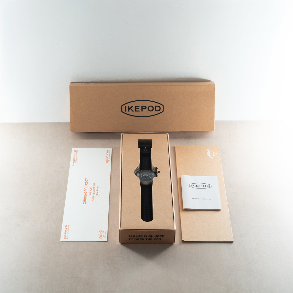 Black Ikepod Chronopod chronograph watch with black rubber strap displayed in branded box with documentation.