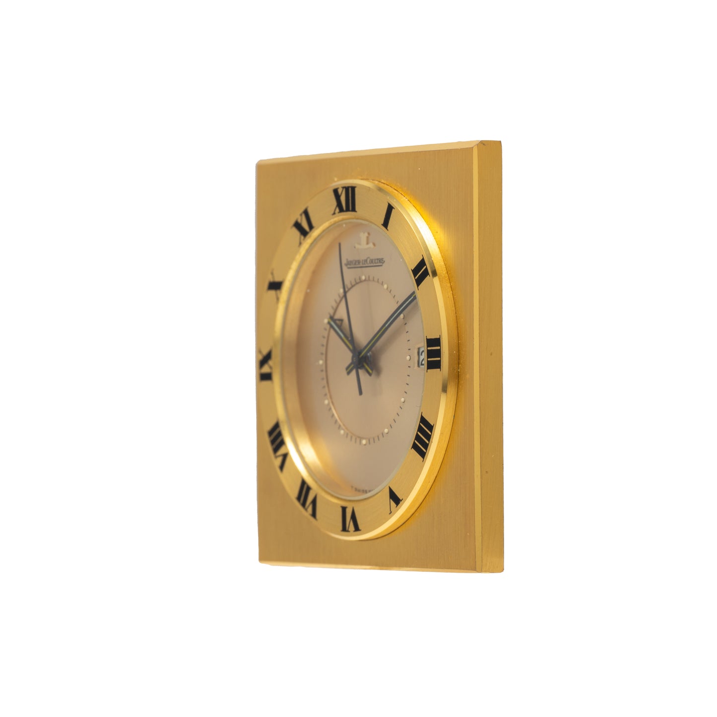 A Jaeger-LeCoultre Memovox Travel Calendar Alarm Clock by Jaeger LeCoultre, featuring black Roman numerals on its round face set to 10:10, is displayed against a white background.