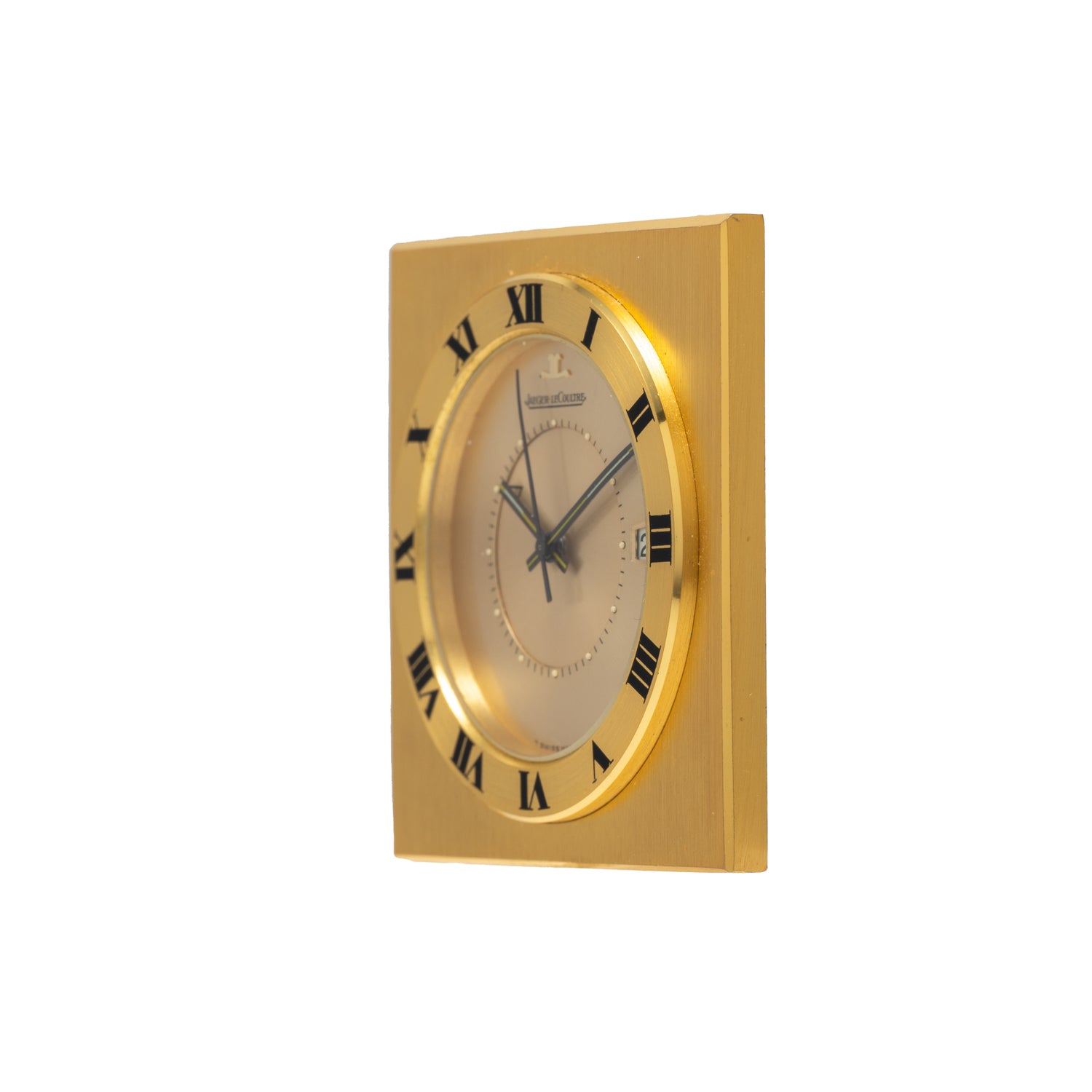 A Jaeger-LeCoultre Memovox Travel Calendar Alarm Clock by Jaeger LeCoultre, featuring black Roman numerals on its round face set to 10:10, is displayed against a white background.
