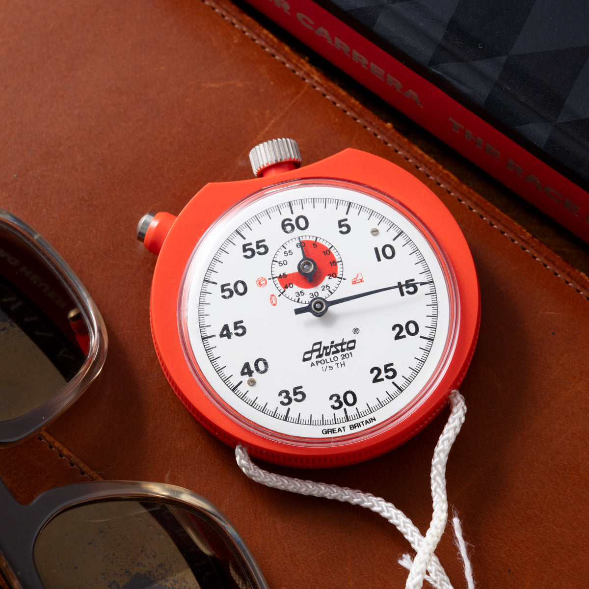Red Aristo Apollo stopwatch with white dial, numbered scale, red subdial, metal crown, and white cord lanyard.