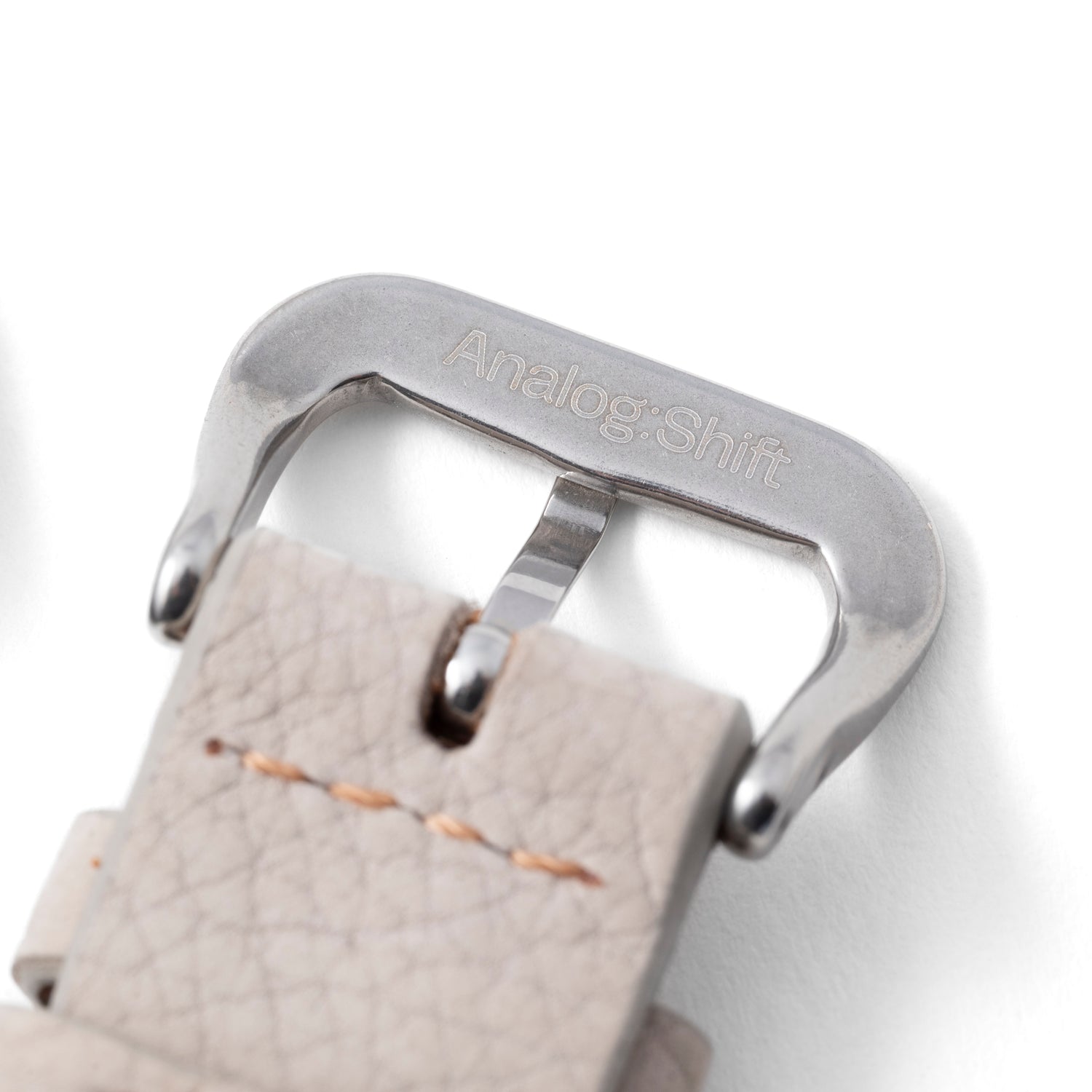 A close-up of a silver Analog:Shift buckle on the Vantage Grey Matte Calf Leather Strap, featuring light beige textured handmade leather and visible stitching.