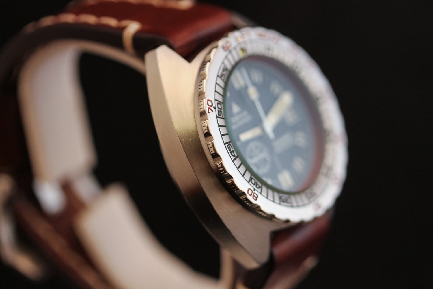 Close-up of the DOXA Sub 300T Sharkhunter Aqua Lung dive watch, featuring a brown leather strap, numbered silver bezel, and dark round face—an iconic DOXA diver’s style—set against a black background.