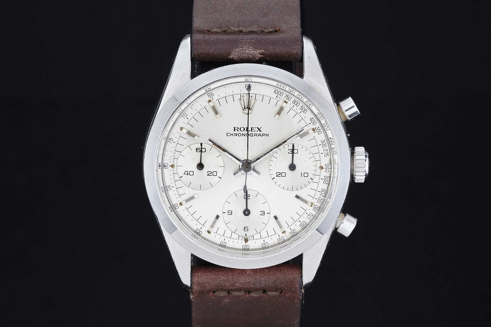 A Rolex Cosmograph 6238 chronograph wristwatch with a white dial, three subdials, silver casing, and brown leather strap is shown against a black background. Description Coming Soon!.