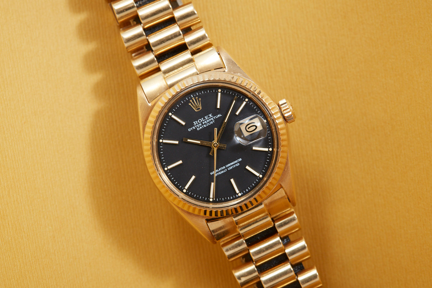 Solid gold vintage Rolex Datejust on yellow background