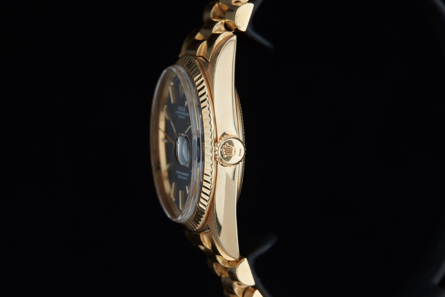 Solid gold vintage Rolex Datejust on black background sideview