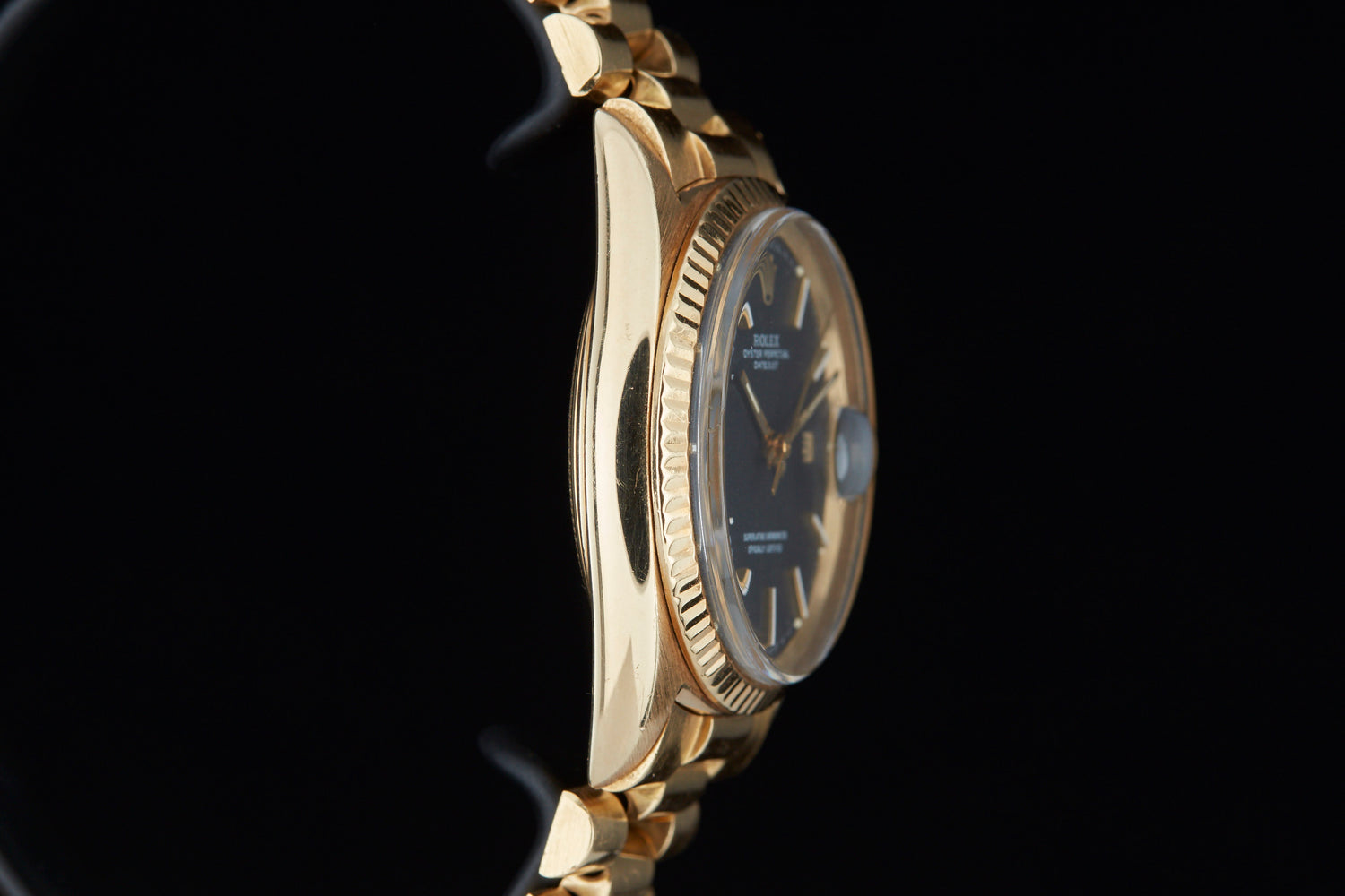Solid gold vintage Rolex Datejust on black background sideview