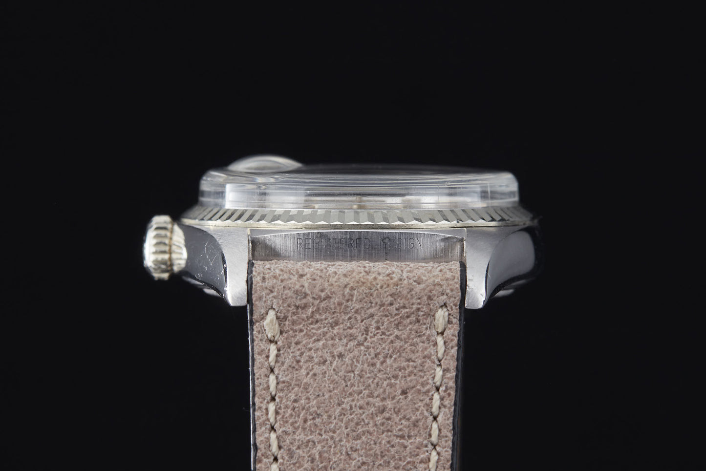 Side view of a silver Rolex Day Date by Rolex, featuring a ridged crown, thick domed crystal, beige leather strap, and automatic movement, set against a solid black background.