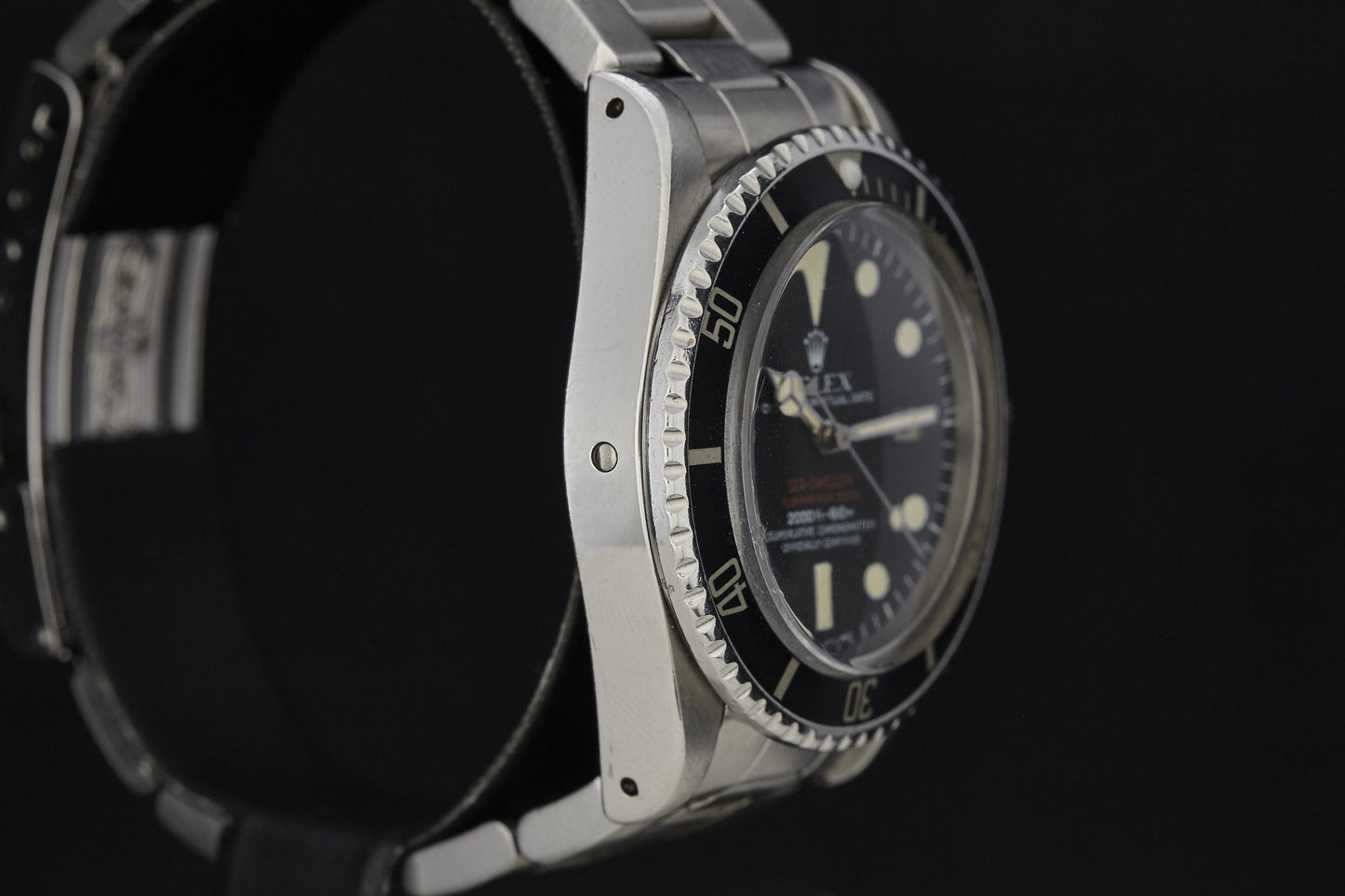 A close-up side view of a vintage Rolex Submariner by Rolex, featuring a black bezel and dial, white hour markers, and a metal bracelet, set against a dark background and reminiscent of classic models.