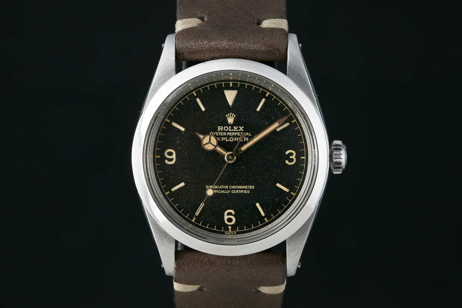 The Rolex Explorer 1016 by Rolex features a black dial, luminous markers, gold-toned hands, and a brown leather strap. Shown against a black background, this vintage wristwatch combines elegance and classic style. Detailed description coming soon!.