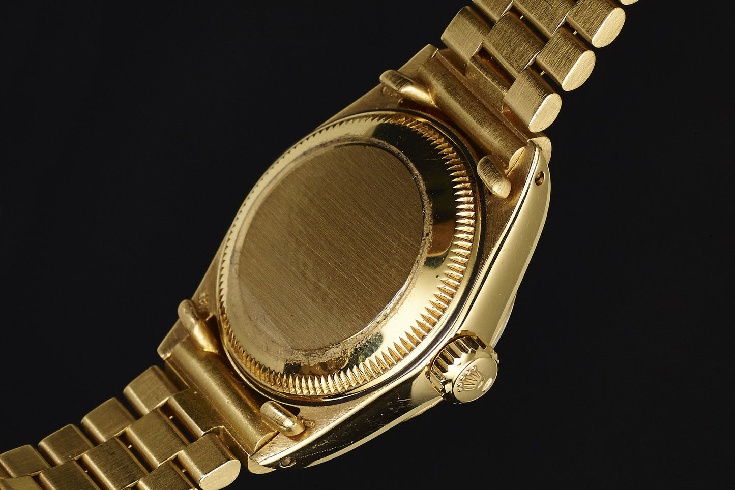Close-up of the Rolex Lady Datejust 18K Mahogany Dial, showcasing its gold link bracelet, crown, and smooth case back in fine detail against a black background.