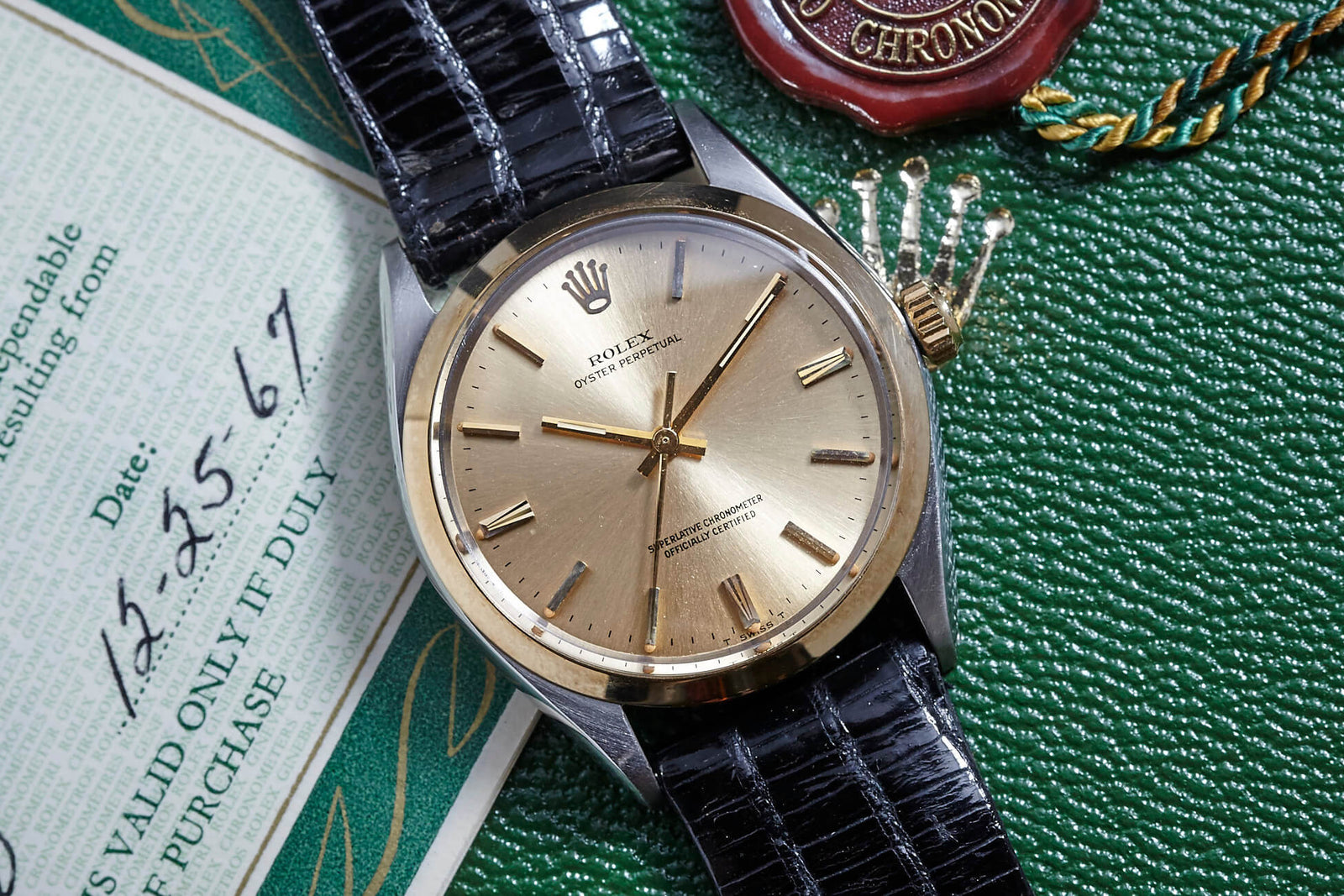A vintage 1967 Rolex Oyster Perpetual with a black leather strap sits on a green textured surface, accompanied by a certificate and a red wax seal with green and gold cord, evoking its original owner's legacy.