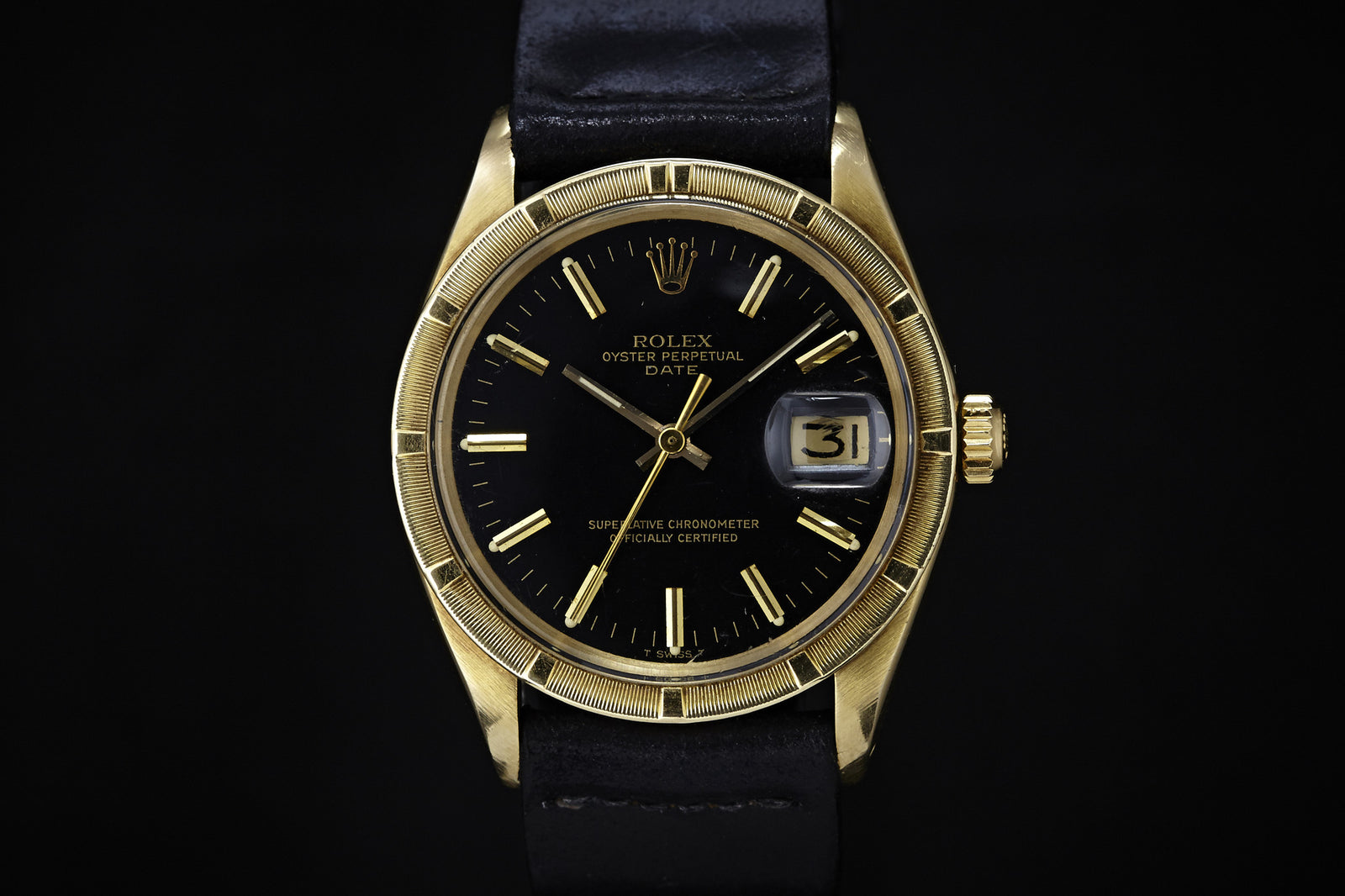 The Rolex Oyster Perpetual Date 14K Black Dial - 1970 features a yellow gold case, black dial with gold hour markers, date display at 3 o’clock under magnification, and a black leather strap—classic style from Rolex.