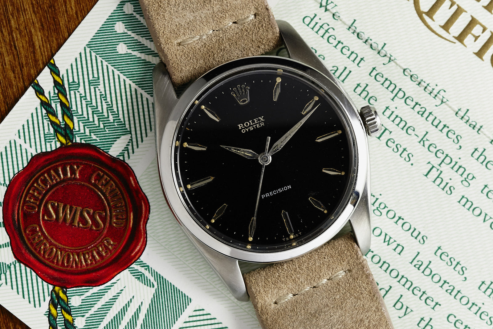A 1959 Rolex Oyster Precision by Rolex, featuring a black dial and tan leather strap, is displayed on its certificate beside a red wax seal stamped SWISS Officially Certified Chronometer.