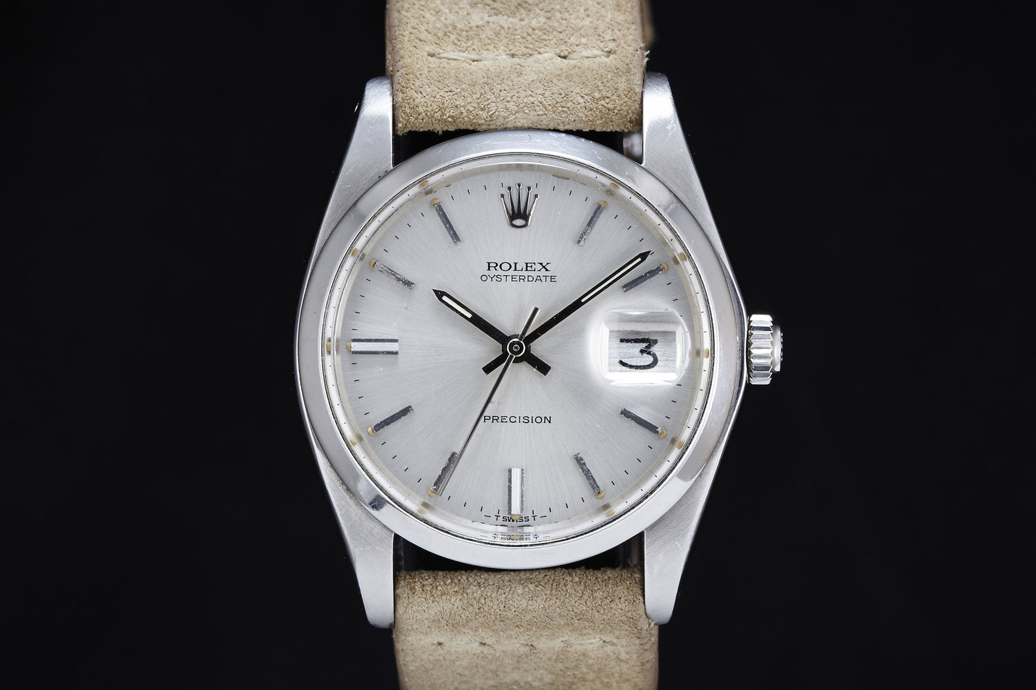 A close-up of the Rolex Oysterdate Precision - 1978 shows a silver case, beige leather strap, white dial with silver hour markers, and a date window at 3. The time reads about 10:10. Brand: Rolex.