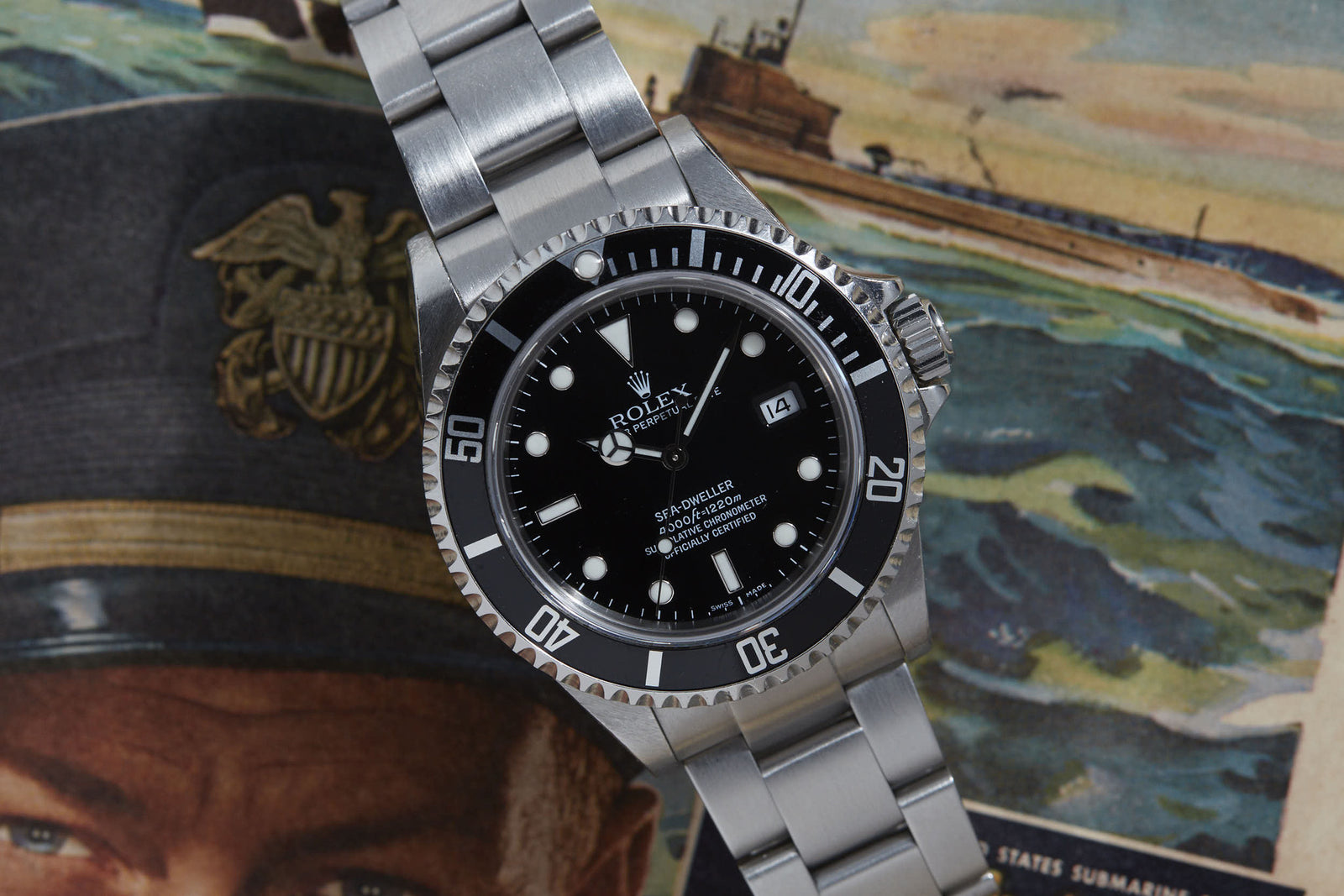 A Rolex Sea Dweller by Rolex, featuring a black dial and silver metal band, rests on a vintage magazine with a naval officer and submarine—a tribute to COMEX divers and the legacy of saturation diving.